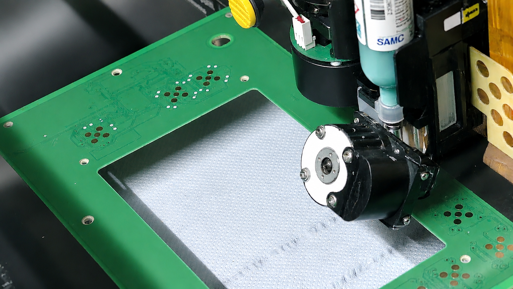 Close-up of an automated PCB assembly head over a green circuit board, preparing to place components.
